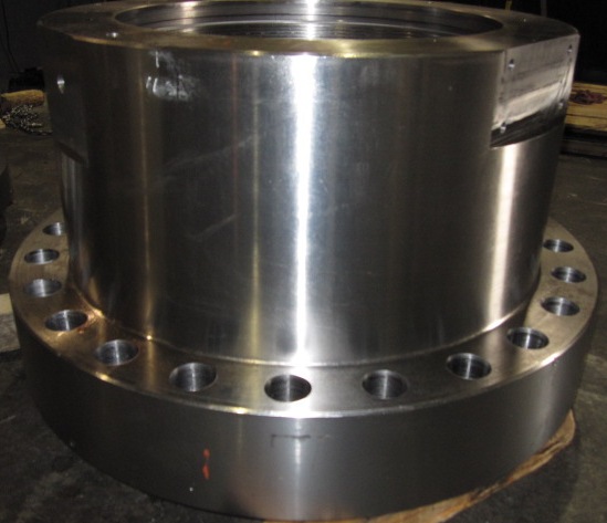 Large machined body flange with a hub and full drilled bolt circle sitting on the shop floor